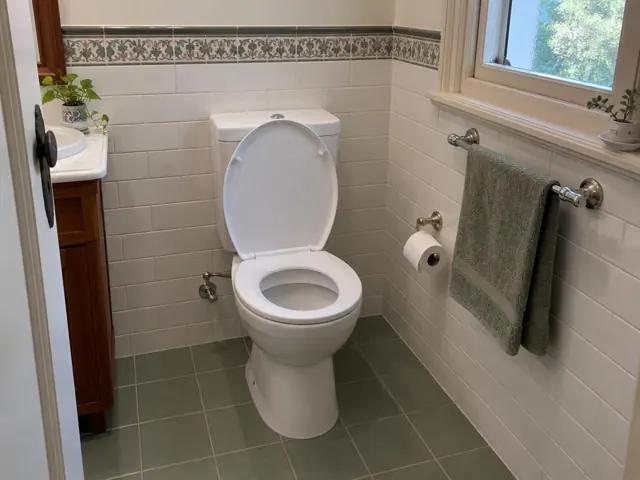 Clean white toilet in a tiled bathroom with towel rail and window in Wahroonga