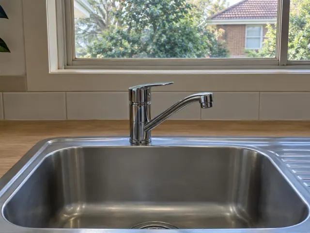 Chrome kitchen tap above a stainless steel sink with a timber benchtop and tiled wall in Turramurra